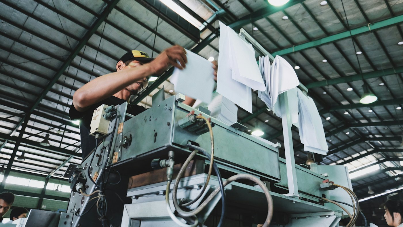 An operator checking paperwork beside an industrial machine
